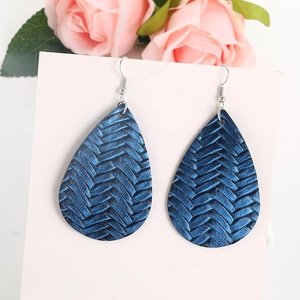 Dettaglio orecchini a goccia blu con trama in pelle intrecciata su cartoncino bianco
