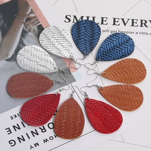 Dettaglio di orecchini a goccia in pelle con trama a treccia in argento, blu, ocra e rosso