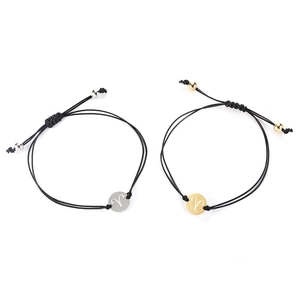 Detail view of Aries zodiac sign charms on black braided bracelets in gold and silver