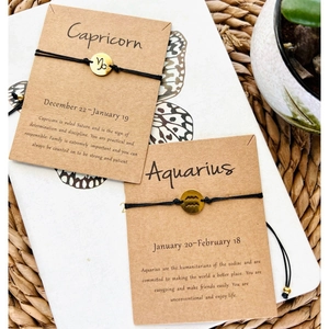 Handmade woven zodiac bracelet with Capricorn and Aquarius gold charms on black cord
