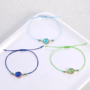 Dettaglio di braccialetti intrecciati a mano con pietre di cristallo e nodi scorrevoli