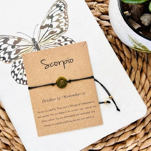 Handmade Scorpio constellation bracelet with gold charm on a black woven cord strap