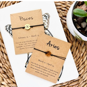 Detailed view of handmade Pisces and Aries zodiac bracelets on kraft paper cards