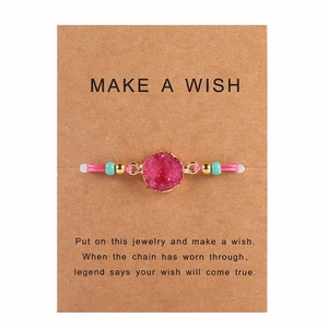 Dettaglio di un braccialetto dei desideri con cristallo rosa su carta e cordino