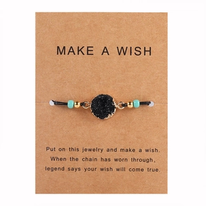 Dettaglio del bracciale artigianale in quarzo druzy su un biglietto d'auguri in kraft
