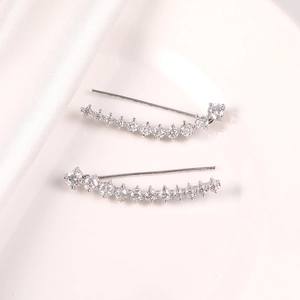Detalle de pendientes trepadores de plata con circonitas blancas sobre seda blanca