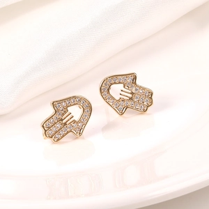 Detalle de pendientes de Mano de Fátima dorados con micro-pavé de circonitas brillantes