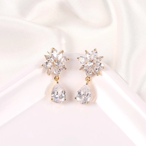 Detalle de pendientes de flores doradas con circonitas marquesa y gotas de cristal