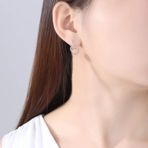 Primer plano de pendientes de aro dorados con forma de corazón y circonitas en modelo
