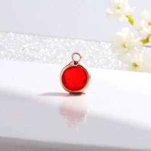 Detail shot of a red crystal birthstone pendant with rose gold metal border for DIY jewelry