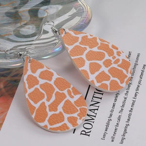 Detailed close-up of waterdrop leather earrings featuring orange giraffe animal print