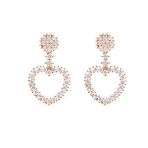 Detalle de pendientes de corazón dorados con pavé de circonitas claras en diseño hueco