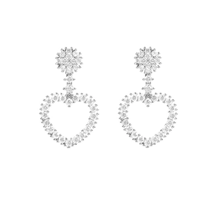 Detalle de pendientes de corazón plateados con botón de flor y pavé de circonitas