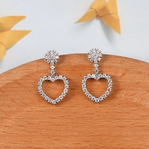Vista macro detallada de pendientes de corazón con pavé de circonitas en acabado plata