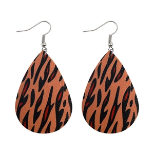 Detail of teardrop leather earrings featuring vibrant orange and black tiger print textures