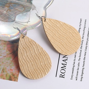 Detail of water drop earrings featuring golden textured faux leather and silver hooks