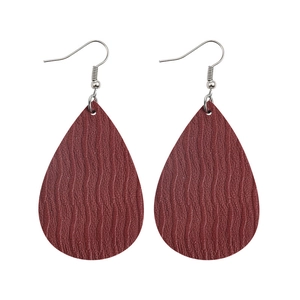 Detail view of burgundy teardrop earrings with embossed wave pattern on faux leather