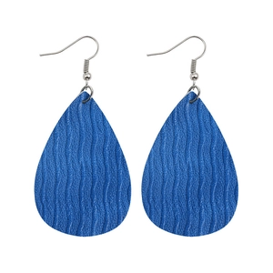 Detailed close-up of blue teardrop leather earrings with textured wave pattern