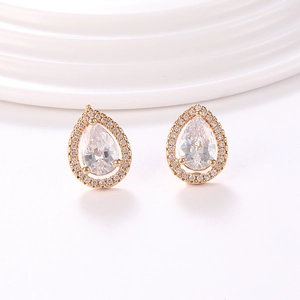 Detalle de pendientes de gota dorados con circonitas blancas y diseño de halo brillante