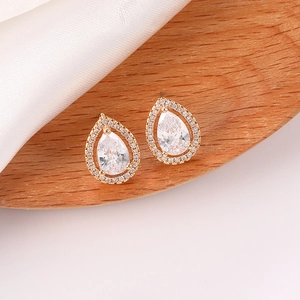 Detalle de pendientes de circonita con forma de pera en un elegante soporte de madera