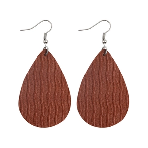 Detail view of brown teardrop earrings with textured wave pattern on a white background