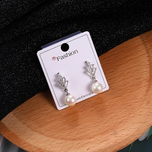 Detalle de los pendientes de plata con circonitas y perlas blancas redondas finas
