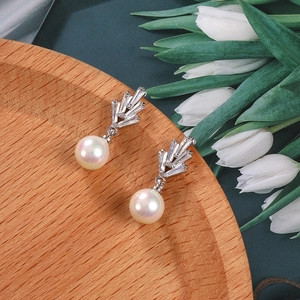 Detalle de pendientes de plata con circonitas blancas y perlas redondas brillantes