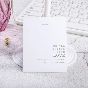 Tarjeta blanca para pulseras con frase motivadora en un soporte de escritorio moderno