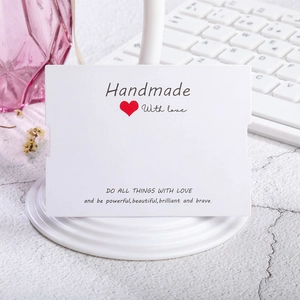 Detalle de tarjeta blanca para joyas Handmade with love con corazón rojo en soporte blanco