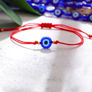 Macro-opname van rode gevlochten Evil Eye armband met blauwe kraal en gouden accenten