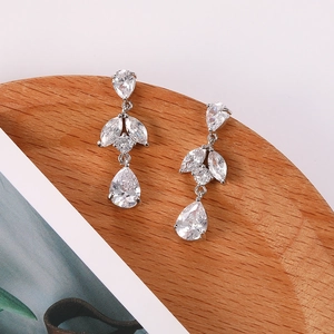 Detalle de pendientes florales de plata con cristales de circón en bandeja de madera