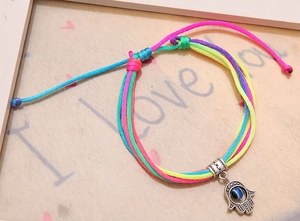 Detail van kleurrijke gevlochten Hamsa-armband met Evil Eye-bedel en verstelbaar koord