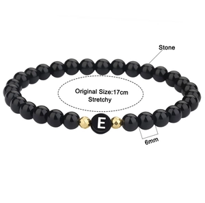 Detail van 6mm zwarte kralenarmband letter E met gouden accenten en 17cm elastiek