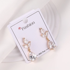 Detalle de pendientes dorados con forma de hoja, circonitas y perno de plata S925