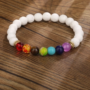 Detailliertes Makro von weißem Lavastein-Chakra-Armband mit sieben farbigen Energieperlen und Gold