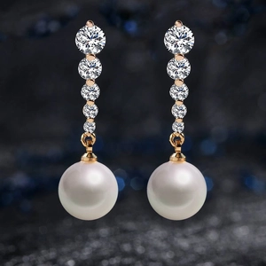 Detalle de pendientes colgantes de oro rosa con cinco circonitas y una perla blanca