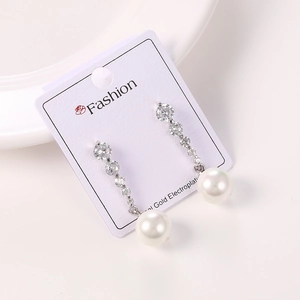 Detalle de pendientes de lujo con circonitas y perla blanca en tarjeta de exhibición