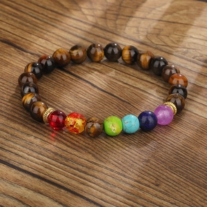 Makroaufnahme des Tigerauge Chakra-Armbands mit sieben Energiesteinen auf dunklem Holz
