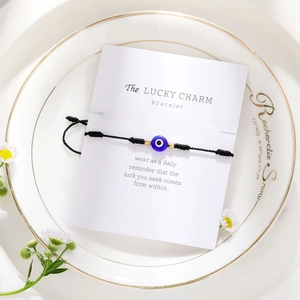 Close-up van blauwe Evil Eye geweven armband met gouden kralen op een witte cadeaukaart