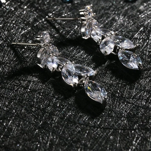Detalle macro de pendientes de plata con circonitas de corte marquise y diseño de hojas