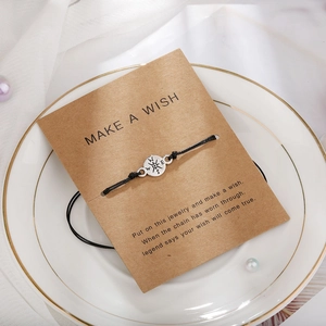 Dettaglio del bracciale con bussola su carta dei desideri con perle e decoro