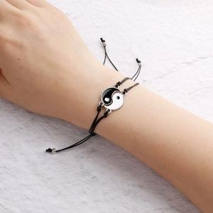 Detail eines handgewebten schwarzen Kordelarmbands mit Yin-Yang-Emaille-Anhänger