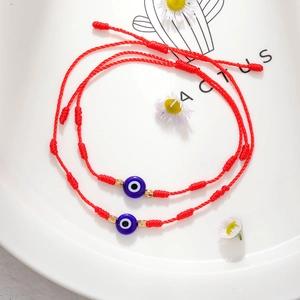 Detail van rode gevlochten Evil Eye-armbanden met blauwe harskralen en verstelbaar koord