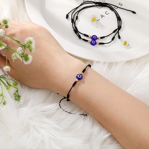 Detail van handgemaakte evil eye armband met blauwe kraal en verstelbaar zwart koord