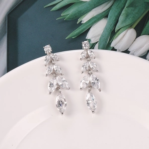 Primer plano detallado de pendientes con circonitas marquise sobre cerámica blanca