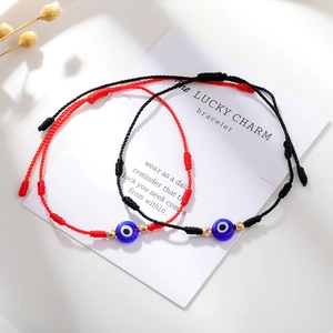 Detail van rode en zwarte gevlochten Evil Eye armbanden met gouden kralen op kaart