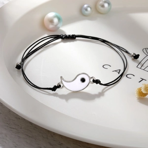 Nahaufnahme des gewebten schwarzen Armbands mit weißem Yin-Yang-Anhänger und Silberperlen