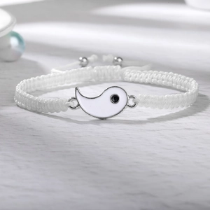 Nahaufnahme des handgewebten weißen Armbands mit Yin-Yang-Anhänger und Zugverschluss