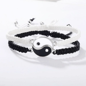 Detailansicht der Yin Yang Anhänger an verstellbaren schwarz-weißen gewebten Armbändern
