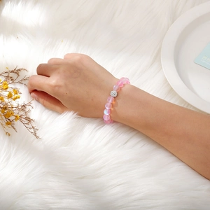 Pink matte moonstone beaded bracelet with silver rhinestone accent on plush background